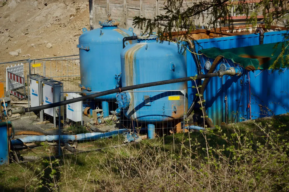 Multiple blue water storage tanks with piping and pumping equipment at an industrial jobsite installation