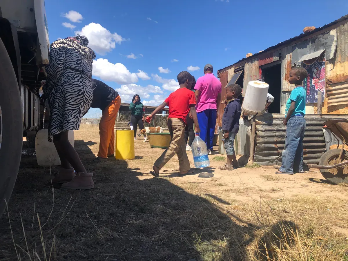 Water tanker truck delivering water to residents in informal settlement during water shortage crisis