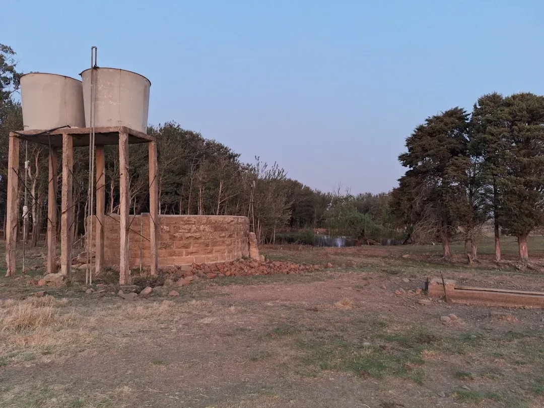 Elevated water storage tanks on metal frame with brick pump house at rural residential property