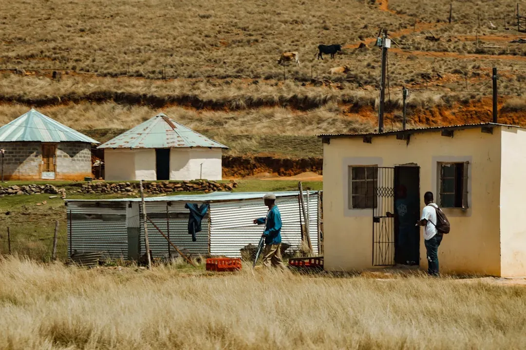 Rural South African homestead with corrugated metal water storage tanks and traditional round tanks, showing community water management infrastructure