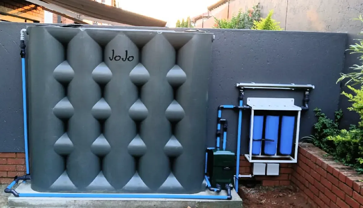 JoJo water tank installed at residential property with blue plumbing connections and filtration system