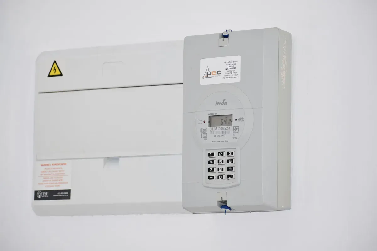 Digital water meter with Itron display showing cubic meter reading and keypad on wall-mounted installation