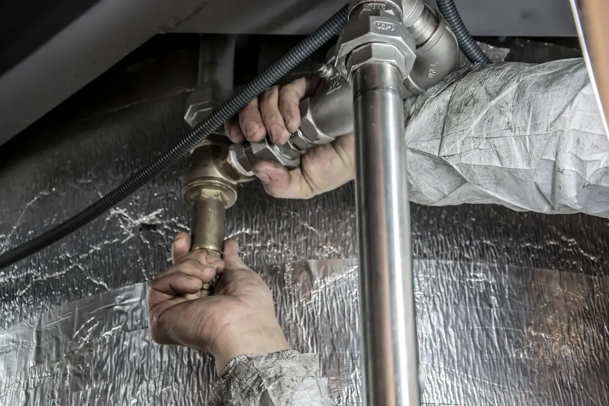 Plumber installing water filtration cartridge and connectors during maintenance work